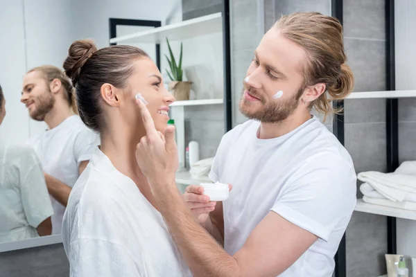 Casal aplicando creme facial — Fotografia de Stock