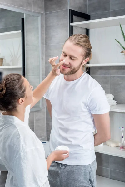 Casal aplicando creme facial — Fotografia de Stock