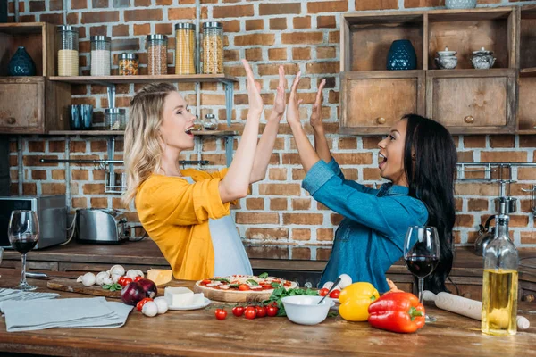Mujeres con pizza en la cocina - foto de stock