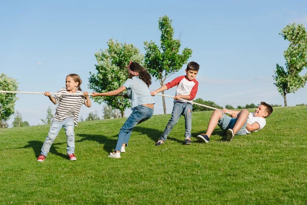 Niños jugando tirón de la guerra - foto de stock