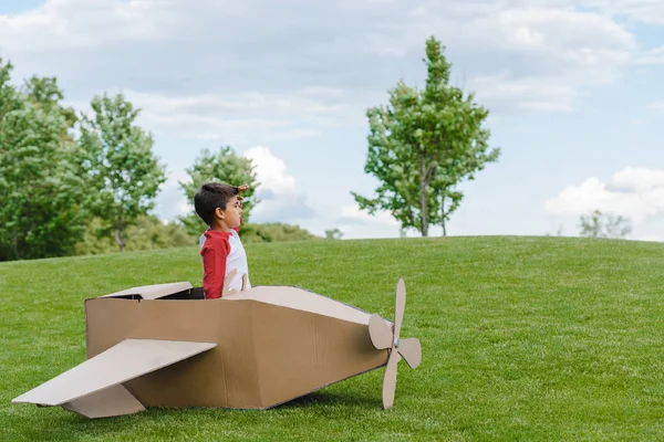 Мальчик, сидящий в картонном самолете — стоковое фото