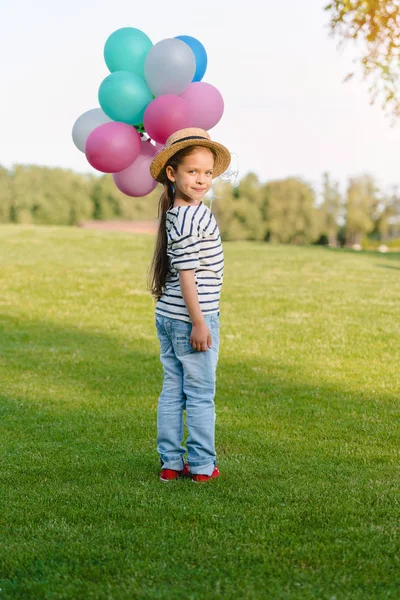 Chica con globos de colores en el parque - foto de stock
