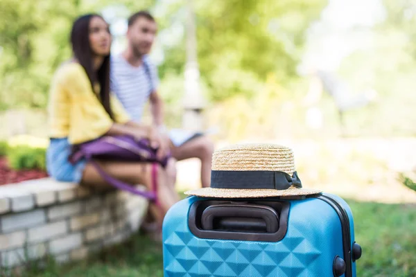 Suitcase and straw hat in park — Stock Photo