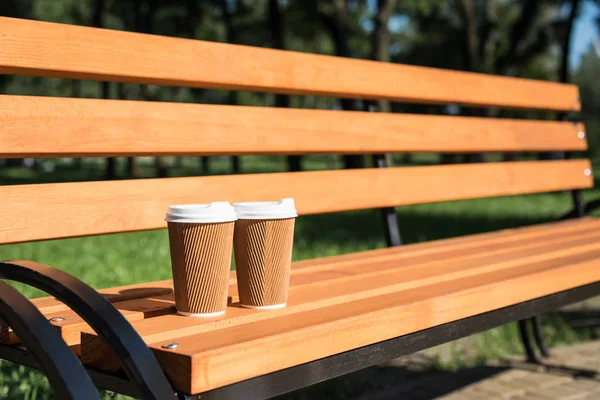 Tasses à café jetables sur banc — Photo de stock