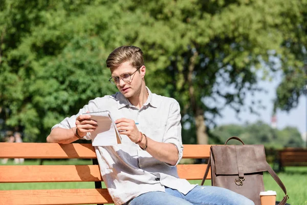 Junger Mann schreibt in Notizbuch — Stockfoto