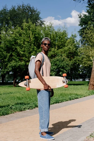 Hombre afroamericano con longboard - foto de stock