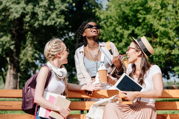 Mujeres multiculturales descansando en el banco en el parque - foto de stock