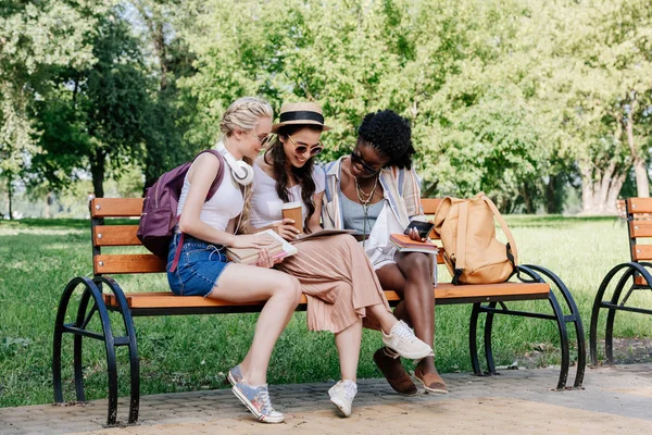 Mujeres multiculturales utilizando tableta en el parque - foto de stock