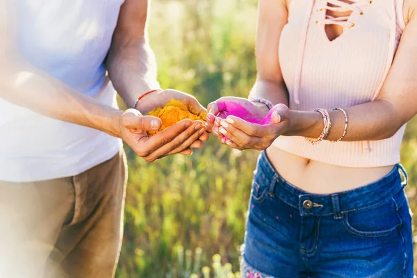 Couple holding colorful dust in hands — Stock Photo