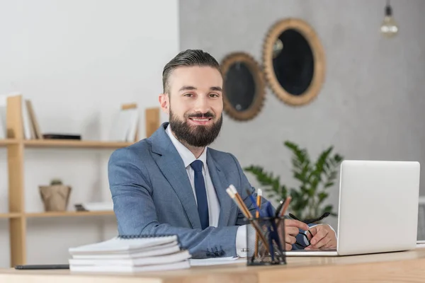 Бизнесмен, сидящий на рабочем месте с ноутбуком — стоковое фото