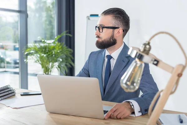 Uomo d'affari seduto sul posto di lavoro con computer portatile — Foto stock