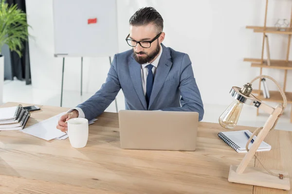 Uomo d'affari con tazza di caffè sul posto di lavoro — Foto stock