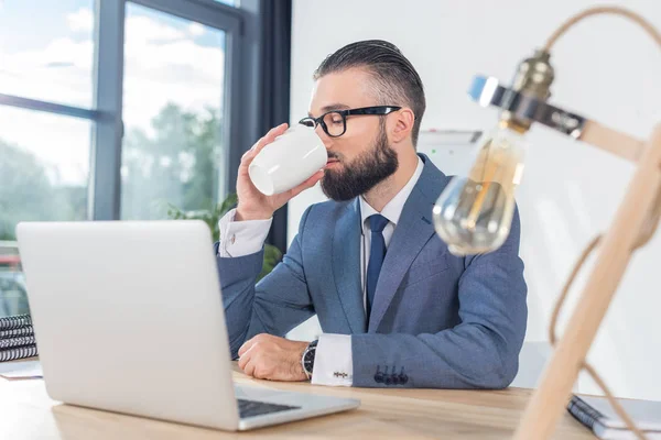 Businessman drinking coffee at workplace — Stock Photo