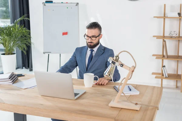 Бизнесмен, сидящий на рабочем месте с ноутбуком — стоковое фото