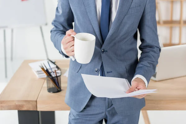 Uomo d'affari con tazza di caffè e carte — Foto stock