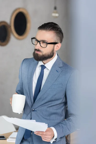 Homem de negócios com xícara de café e papéis — Fotografia de Stock