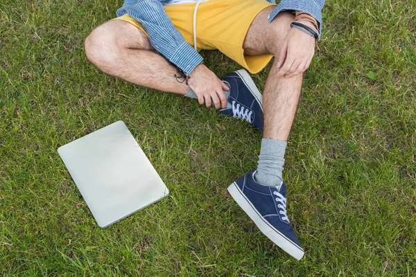 Homme avec ordinateur portable assis sur l'herbe — Photo de stock