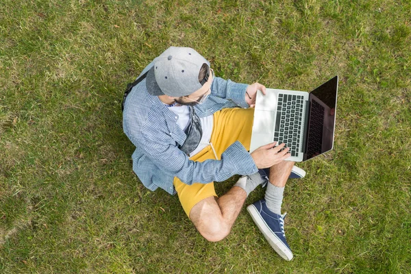 Человек с ноутбуком сидит на траве — Stock Photo