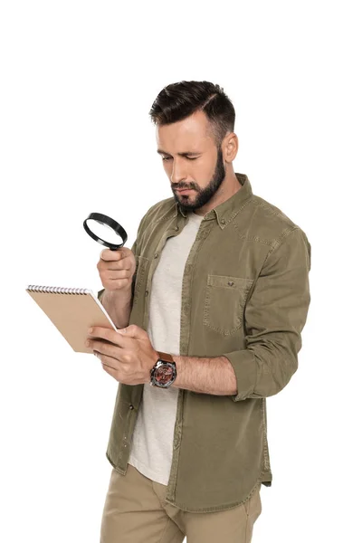 Человек с увеличительным стеклом и ноутбуком — стоковое фото