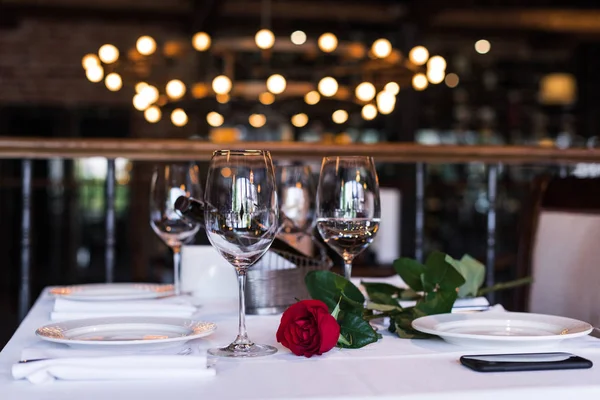 Rosa flor com vinho à mesa no restaurante — Fotografia de Stock