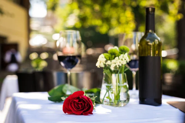 Flor de rosa con vino en la mesa en el restaurante - foto de stock