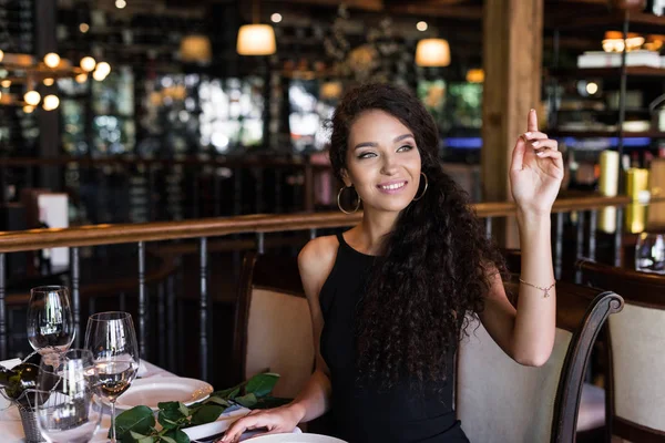 Woman with raised hand in restaurant — Stock Photo