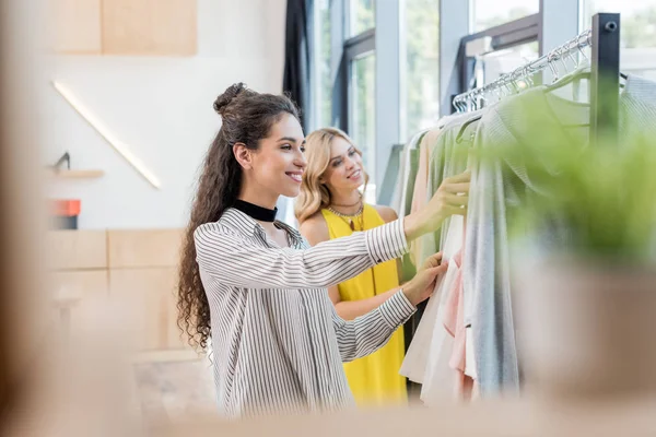 Mujeres eligiendo ropa en sala de exposición - foto de stock