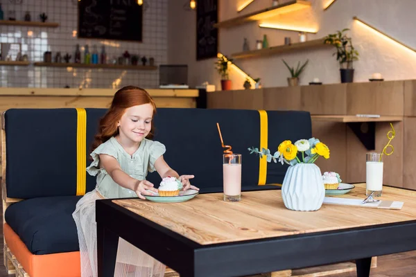 Ragazza mangiare cupcake in caffè — Foto stock