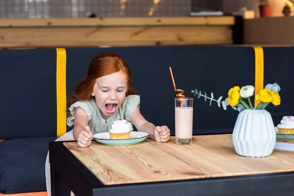 Девушка с кексом в кафе — стоковое фото