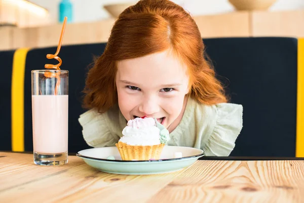 Girl eating cupcake in cafe — Stock Photo