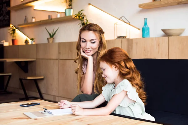 Mother and daughter reading menu in cafe — Stock Photo