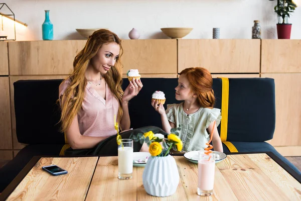 Madre e hija comiendo cupcakes - foto de stock
