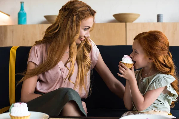 Madre e hija comiendo cupcakes en la cafetería - foto de stock