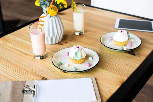 Milkshakes and cupcakes on table — Stock Photo