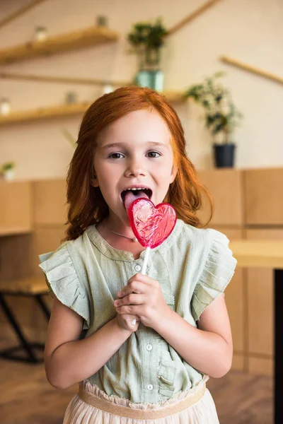 Girl with heart shaped lollipop — Stock Photo