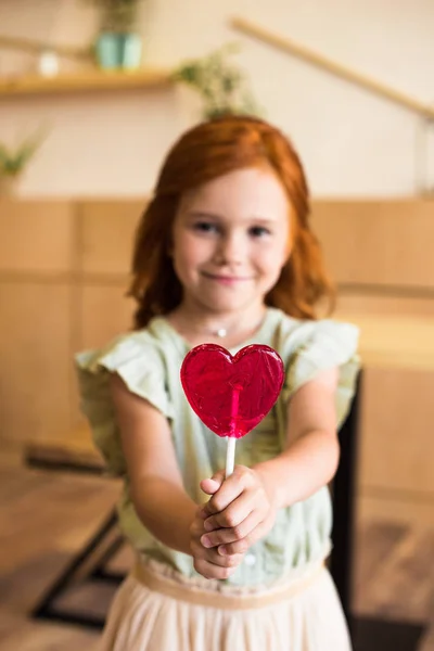 Girl with heart shaped lollipop — Stock Photo