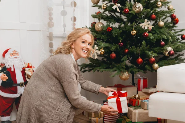 Женщина кладет подарки под елку — стоковое фото