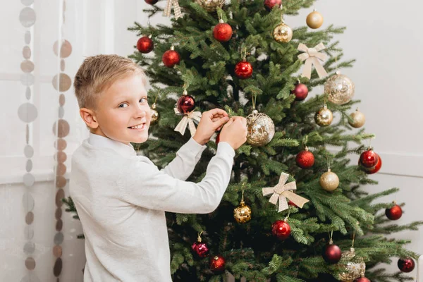 Boy decorating christmas tree — Stock Photo