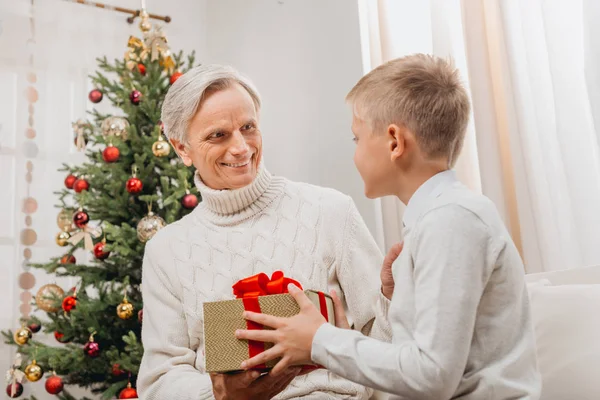 Дедушка преподносит внуку рождественский подарок — стоковое фото