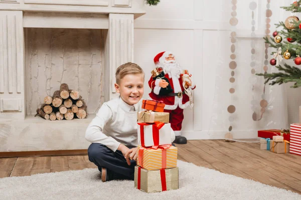 Boy with stack of christmas gifts — Stock Photo