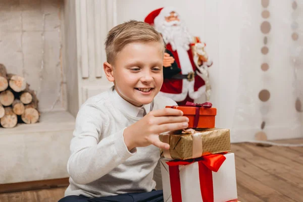 Boy making stack of christmas gifts — Stock Photo