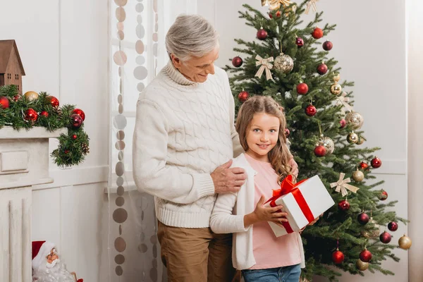 Дедушка и внучка с рождественским подарком — стоковое фото