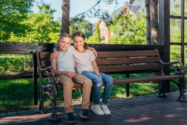 Kids sitting on bench in park — Stock Photo