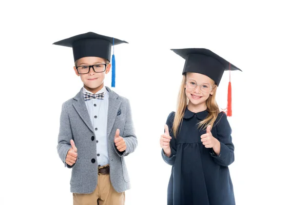 Pupils in graduation hats showing thumbs up — Stock Photo