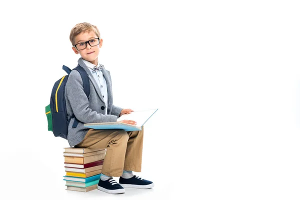 Schoolboy sittting on stack of books and reading — Stock Photo