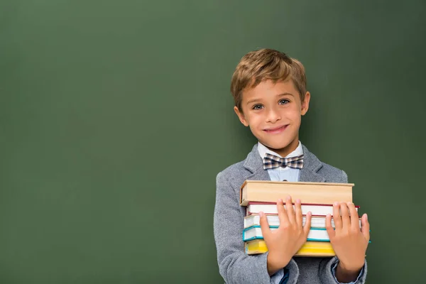 Scolaro sorridente con pila di libri — Foto stock