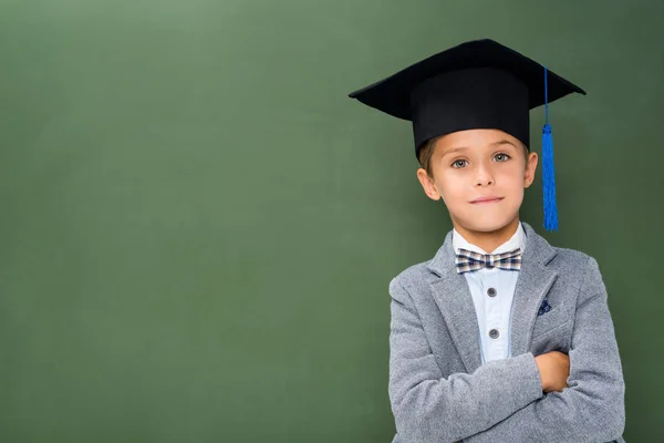 Colegial en sombrero de graduación con brazos cruzados - foto de stock