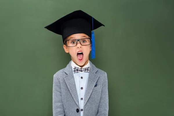 Shocked schoolboy in graduation hat — Stock Photo