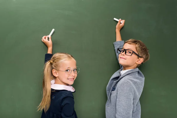 Pupils writing on chalkboard — Stock Photo