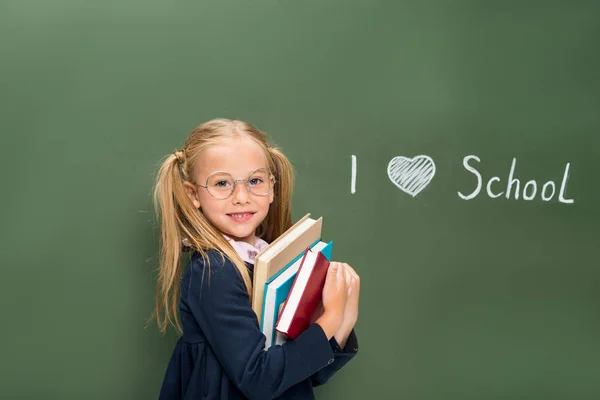 Schoolgirl with pile of books next — Stock Photo